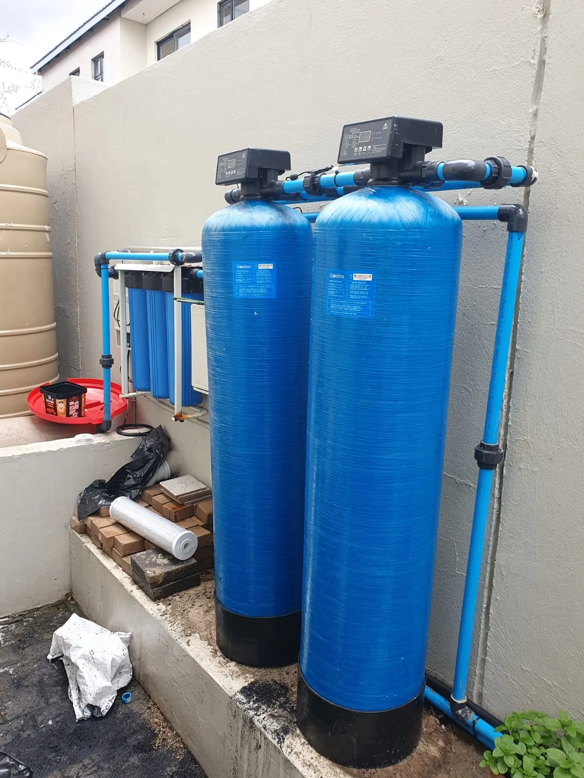Two blue softener vessels and a filter rack piped in beside a water tank